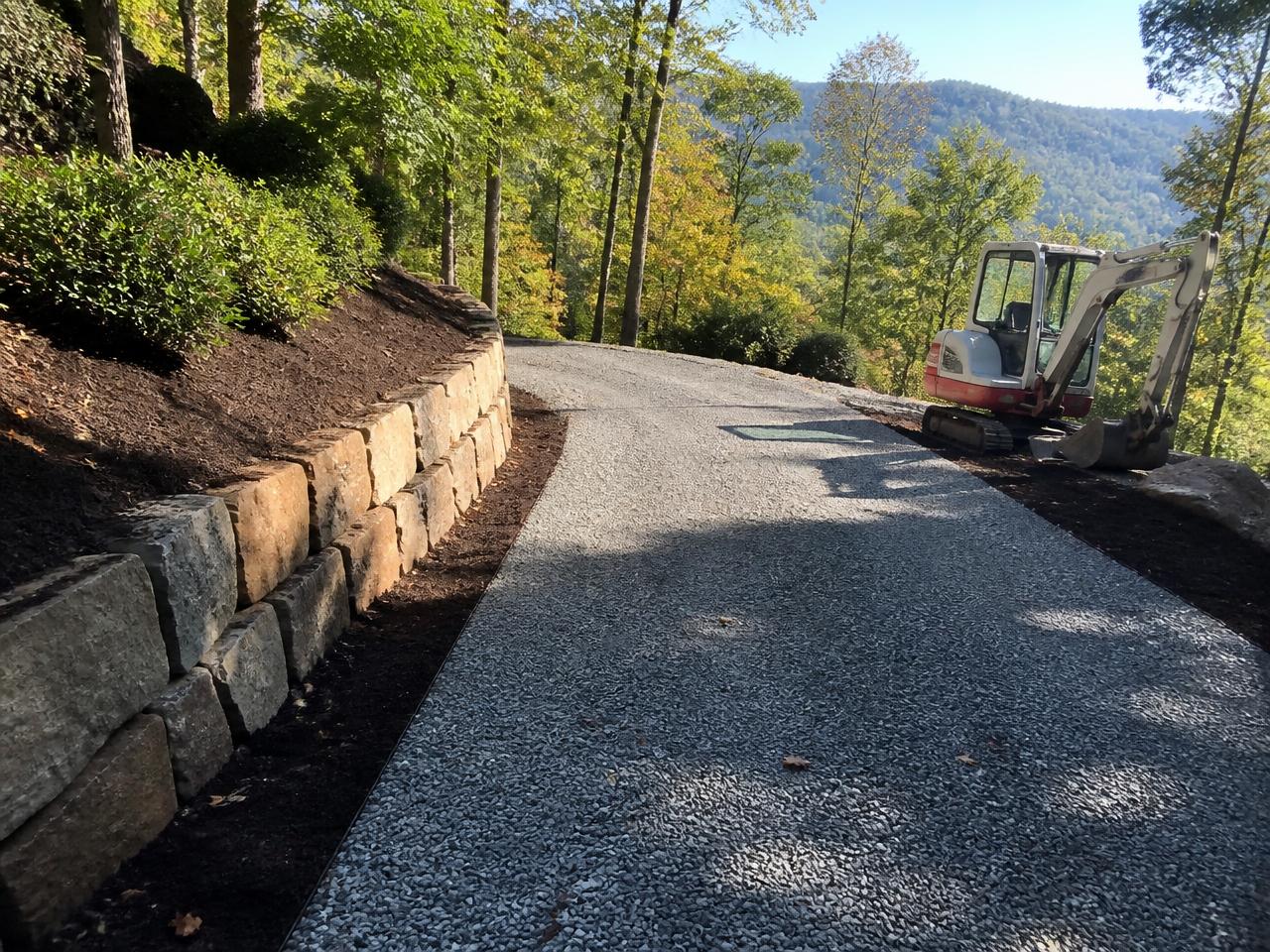 Regraded gravel driveway with a new stone retaining wall and fresh mulch beds